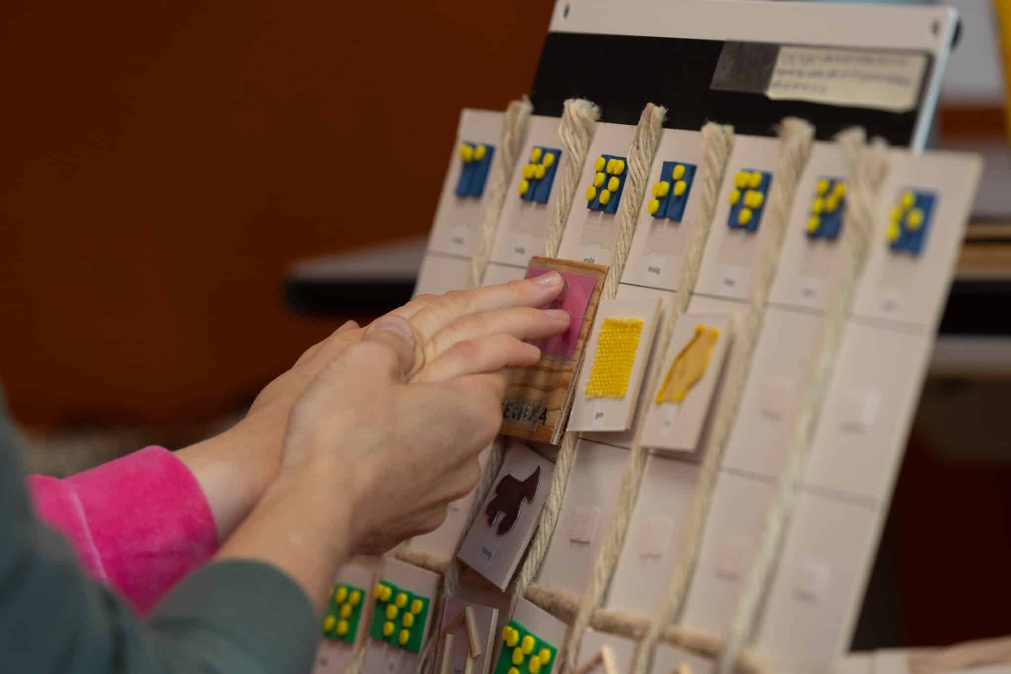 Hender som fører hender over taktilt materiale