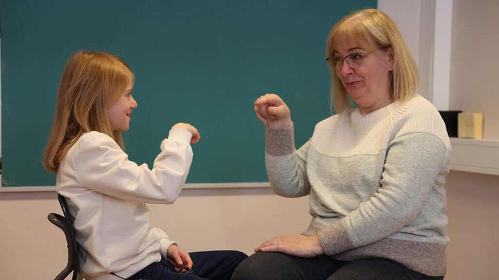 Emma med sin tegnspårklærerer hjemme i Harstad. De sitter overfor hverandre og bruker tegnspråk