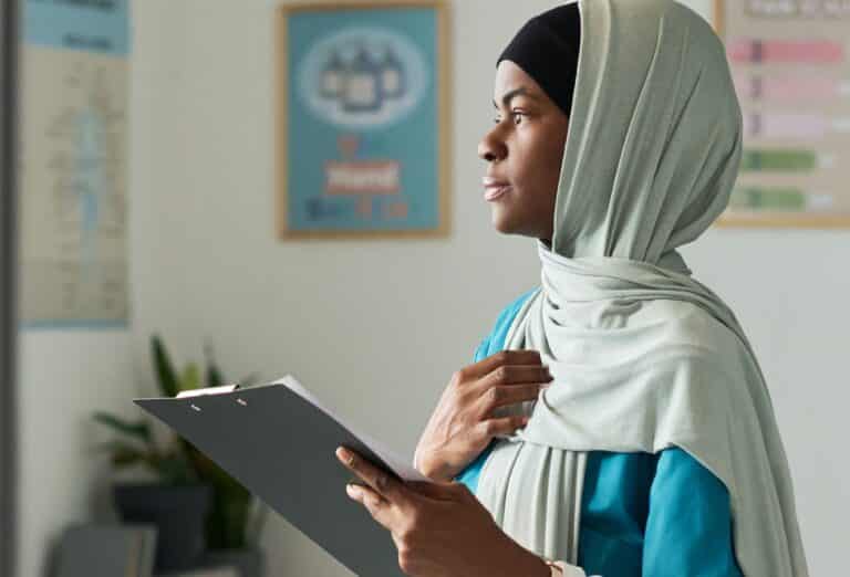 Jente med hijab som ser opp fra et ark