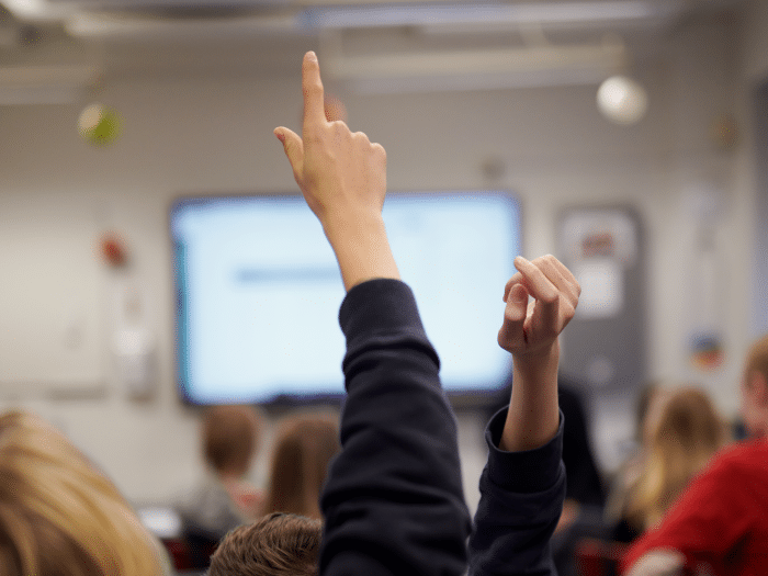 Elever rekker opp hånden i klasserom