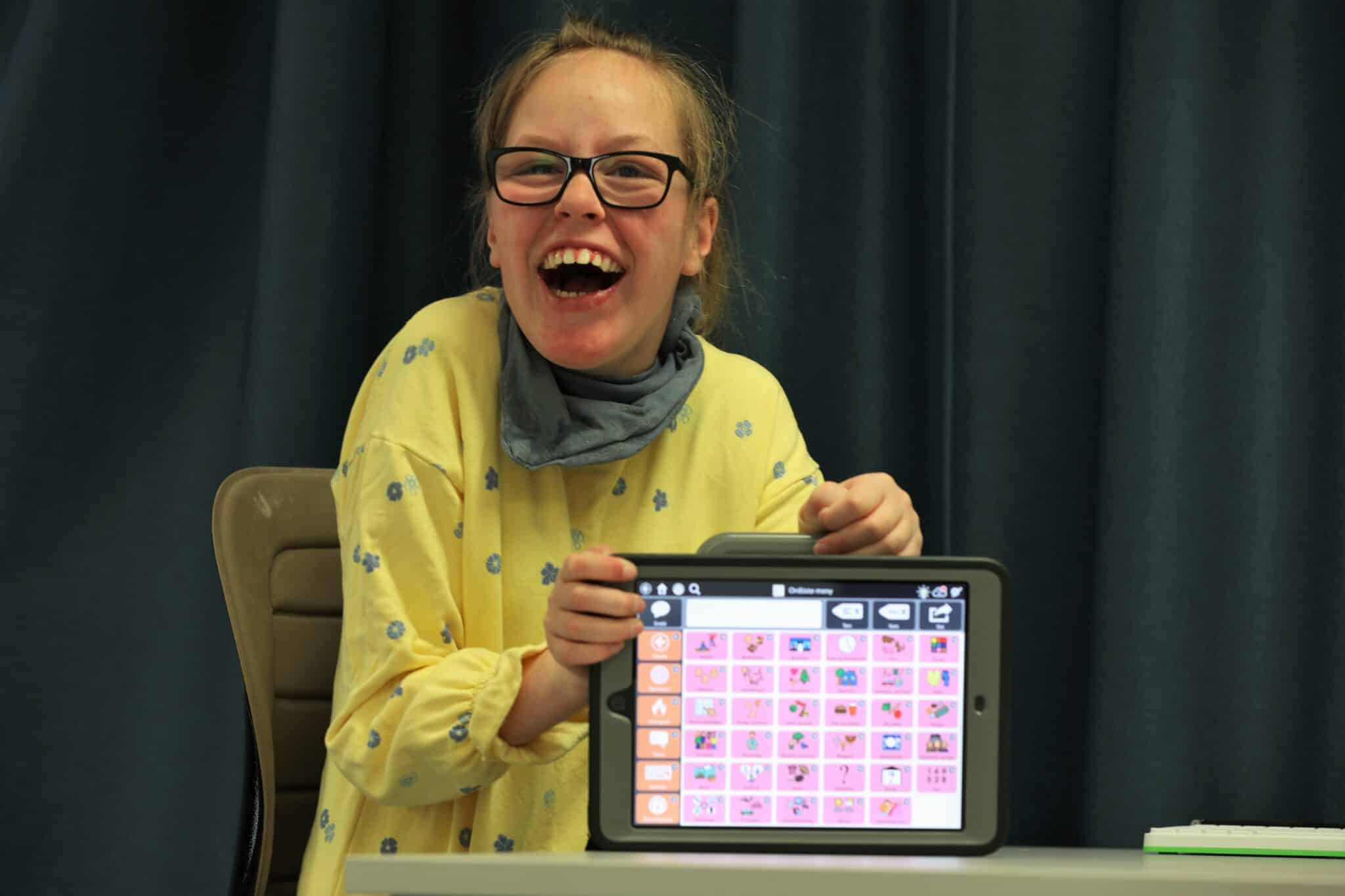 Jente som smiler, holder en skjerm med grafiske symboler