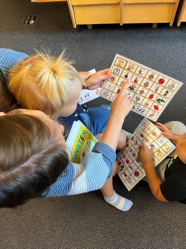 Voksen med barn på fanget og ved siden av, peker på grafiske symboler