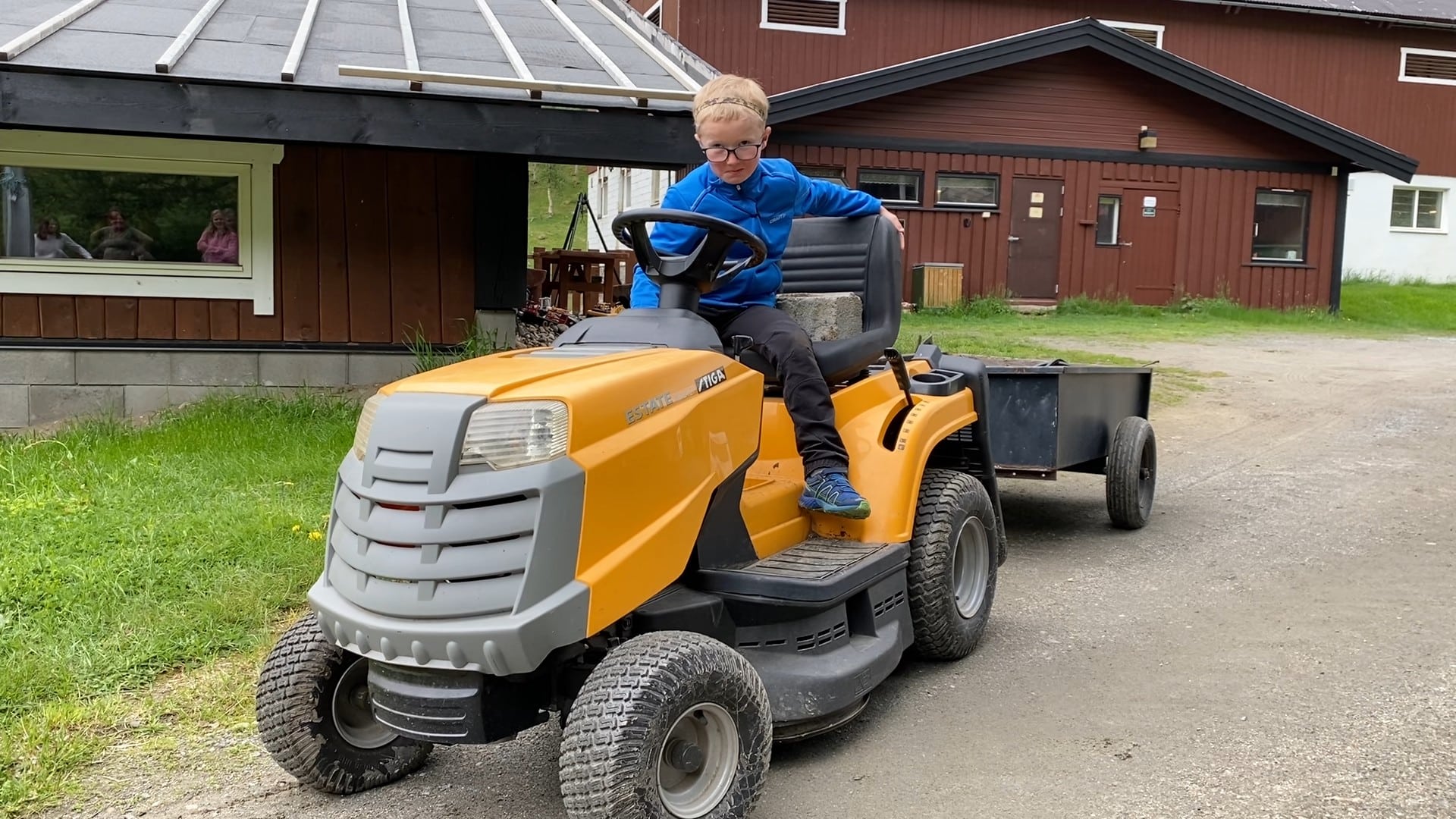 Einar (6) sitter på en leketraktor med tilhenger utenfor hjemmet hans på en gård i Lom