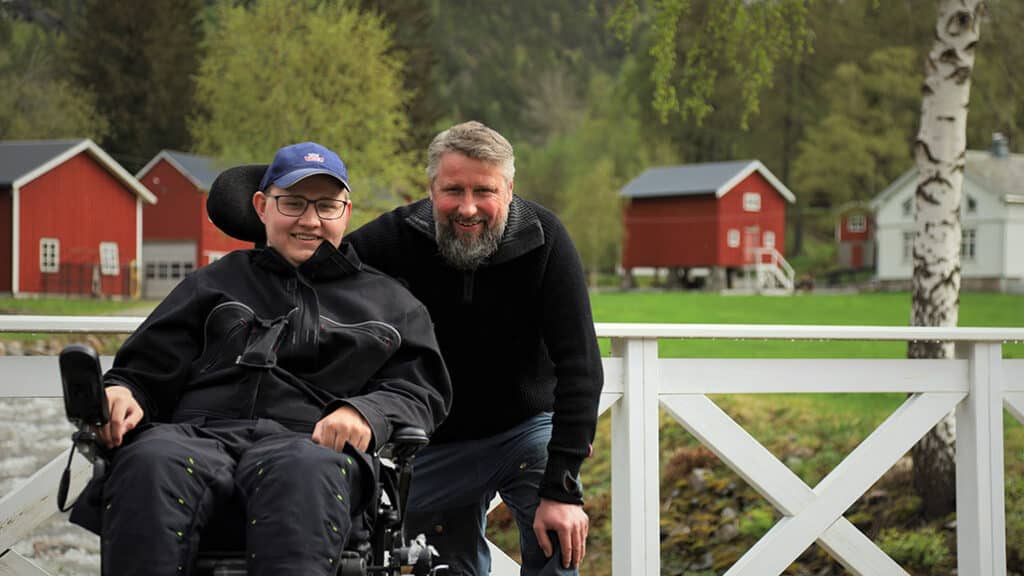 Bilde av John Inge og far foran gården med gårdsbygninger