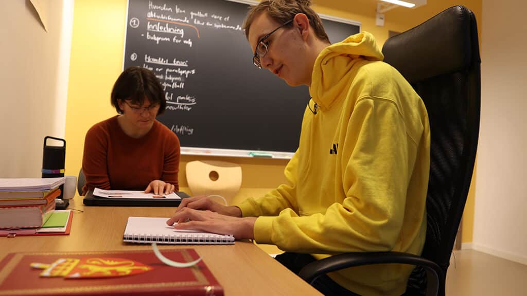 Lærere og Sondre leser punktskrift,. Sitter på hver sin stol og leser hver sin bok.