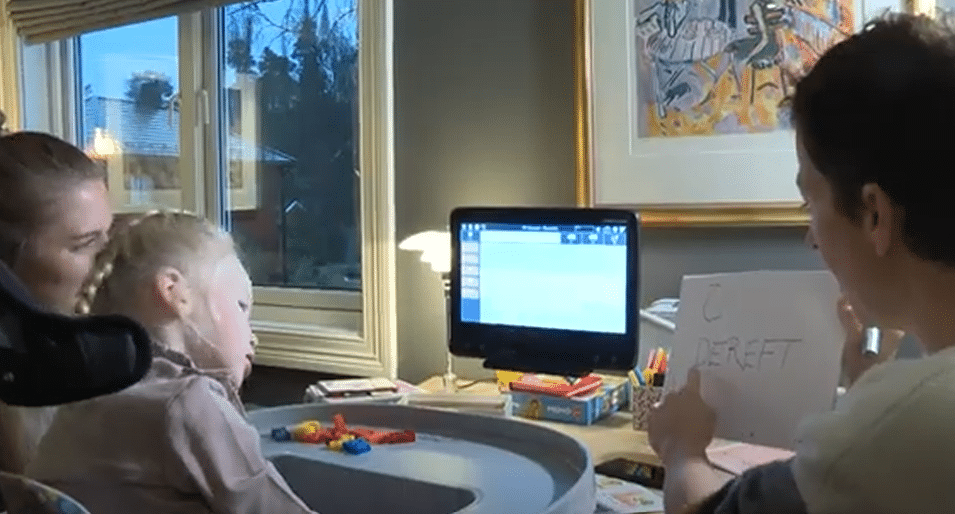 En dame som peker på noen bokstaver. Jente som titter