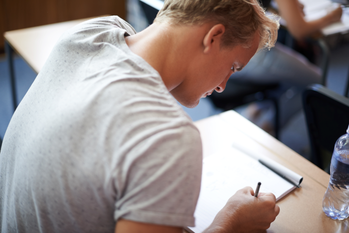 Student sitter ved pult på forelesning