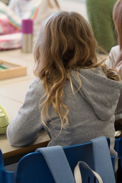 Jente med ryggen til som sitter å leser