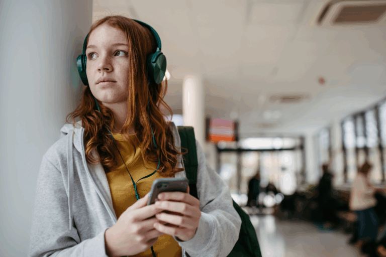 jente med hodetelefoner og mobil i gang på en skole