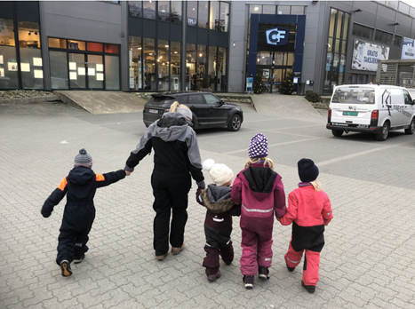 En barnehageansatt og fire barn på vei inn i byggvarehandelen