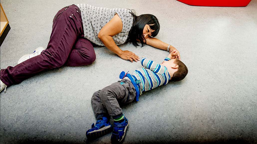 Barn og assistent ligger på gulv vendt mot hverandre