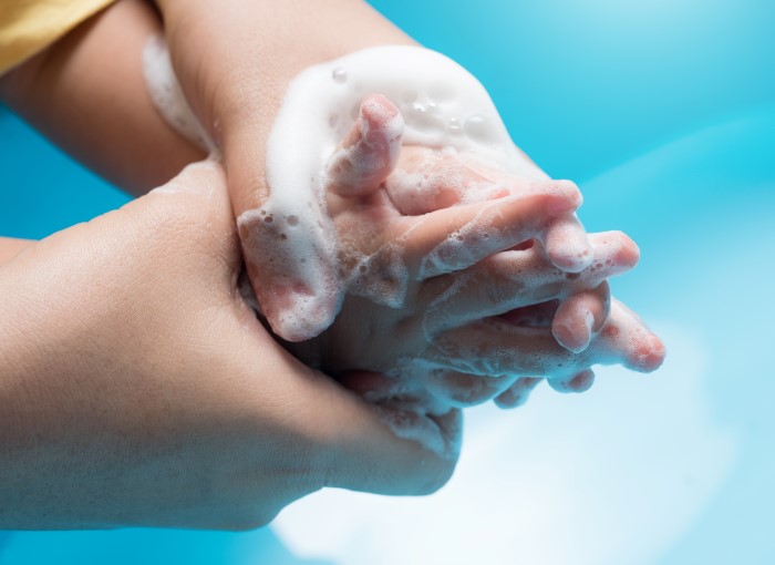 Voksne hender som holder rundt barnehender mens de gnir seg inn med såpe.